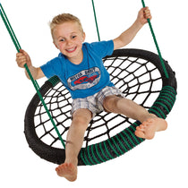 Boy swinging in the oval nest swing with green ropes