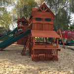 Wooden playground structure with slides and sand area, trees and vehicles in the background