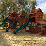 Wooden playground structure with slides and sand area in a park setting