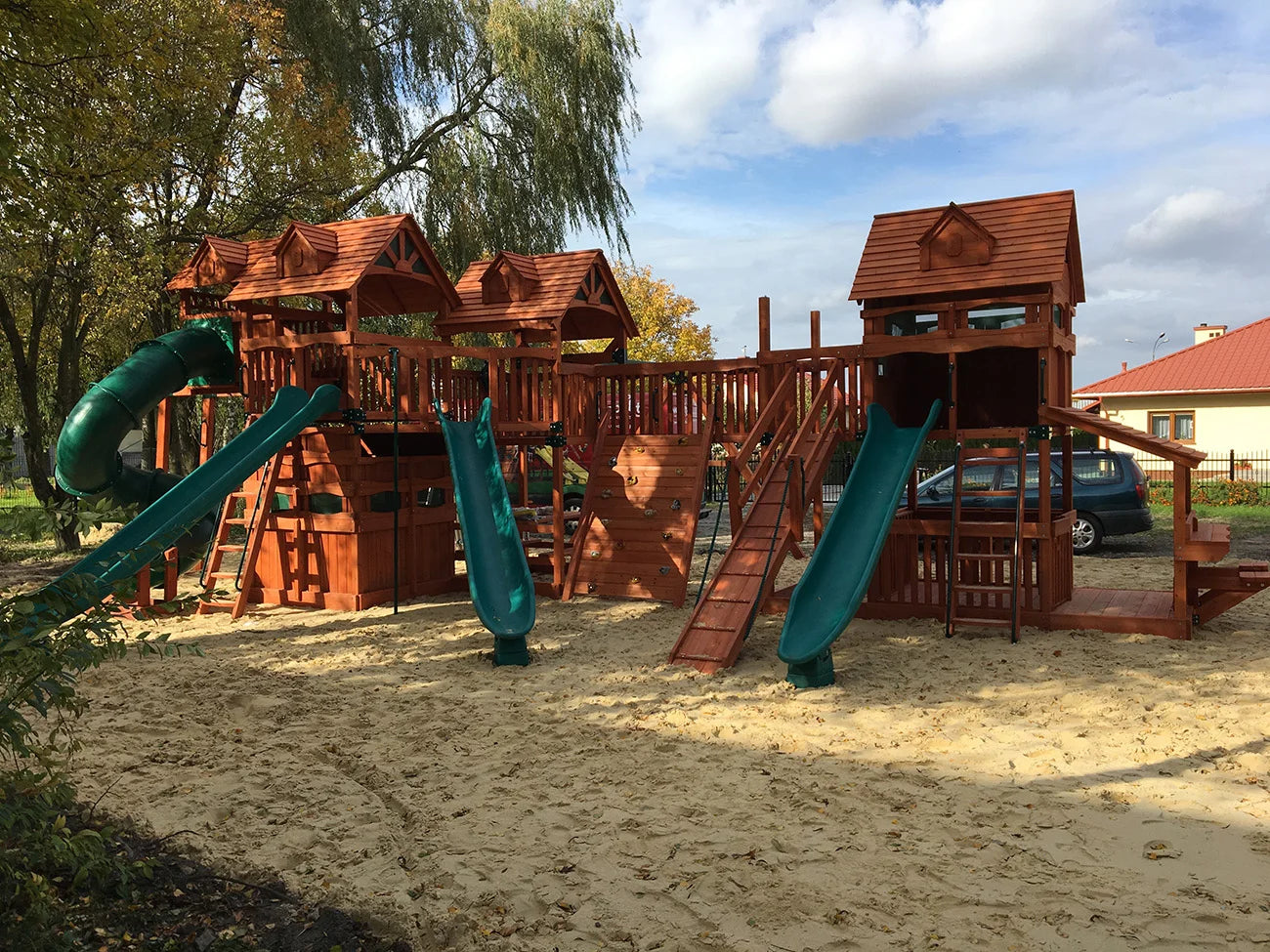 Wooden playground with slides and sand area on a sunny day