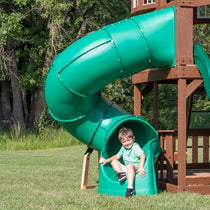 Boy coming out of the green spiral tube slide mounted on a swing set