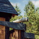 Telescope mounted on the upper fort of the Canyon Creek cedar swing set against pine trees